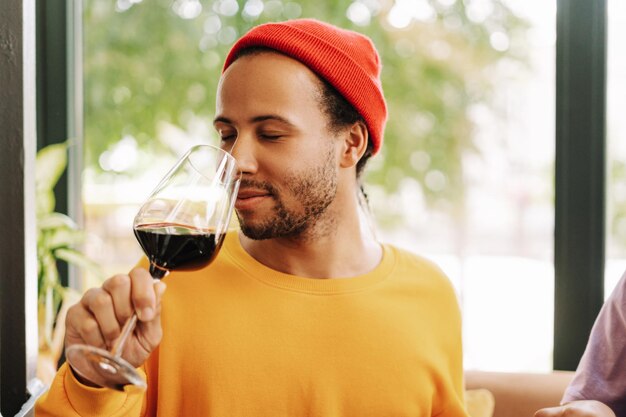 Young Hispanic man enjoying glass of red wine at restaurant