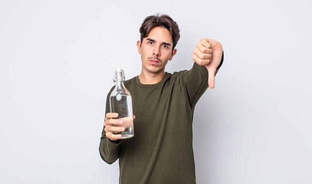 Молодой латиноамериканец чувствует крест, показывает палец вниз. концепция бутылки с водой
