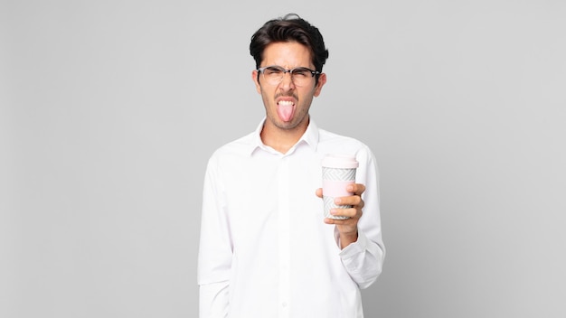 Young hispanic man feeling disgusted and irritated and tongue out and holding a take away coffee