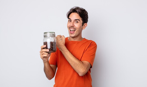 Young hispanic man feeling happy and facing a challenge or celebrating. coffee beans concept