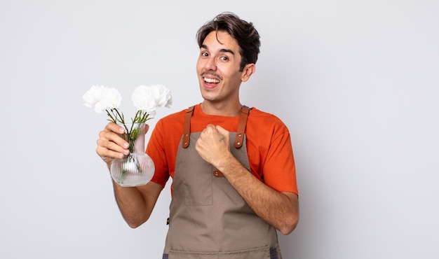 Young hispanic man feeling happy and facing a challenge or celebrating. florist concept