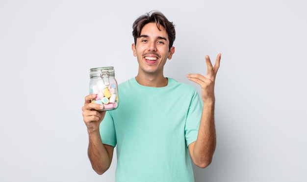 Young hispanic man feeling happy, surprised realizing a solution or idea. jelly candies concept