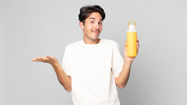 Young hispanic man feeling puzzled and confused and doubting with a coffee thermos