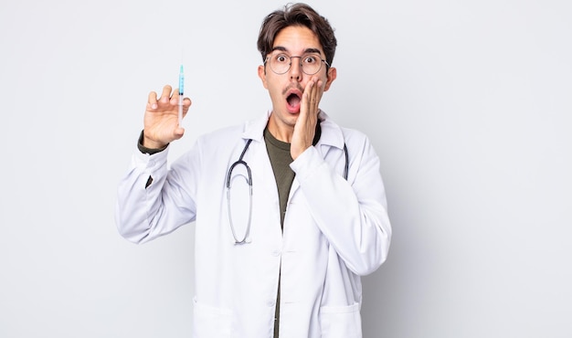 Young hispanic man feeling shocked and scared. doctor syringe concept