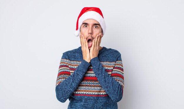 Young hispanic man feeling shocked and scared. new year and christmas concept