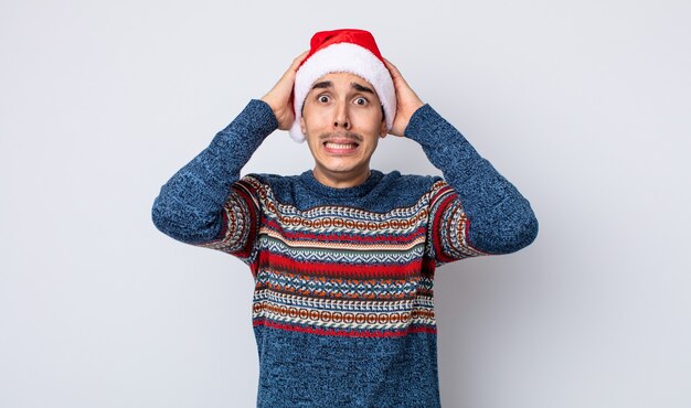 young hispanic man feeling stressed, anxious or scared, with hands on head. new year and christmas concept