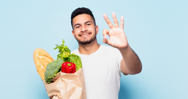 Young hispanic man happy expression. shopping vegetables concept