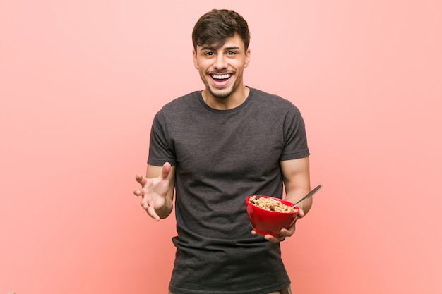 Young hispanic man holding a cereal bowl celebrating a victory or success