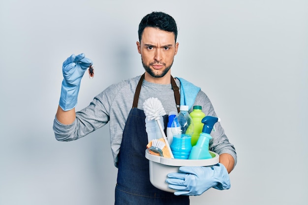 Young hispanic man holding cleaning products and cockroach skeptic and nervous, frowning upset because of problem. negative person.