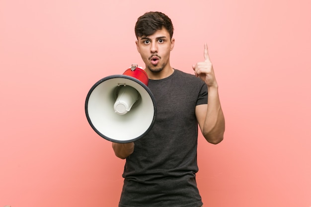 Young hispanic man holding a megaphone having some great idea, concept of creativity.