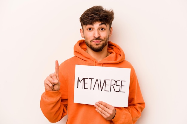 Young hispanic man holding a metaverse placard isolated on white background showing number one with finger