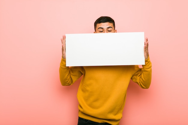 Photo young hispanic man holding a placard