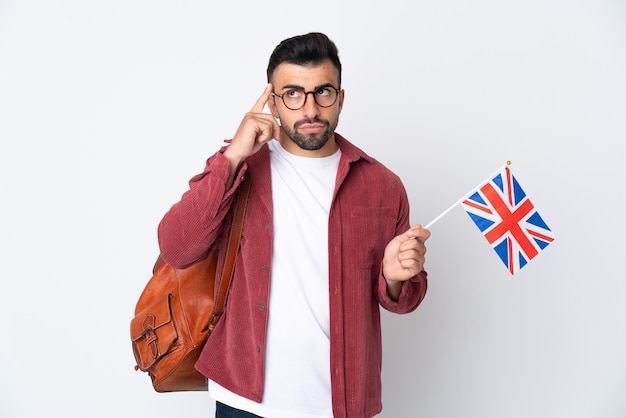 Young hispanic man holding an United Kingdom flag having doubts and thinking