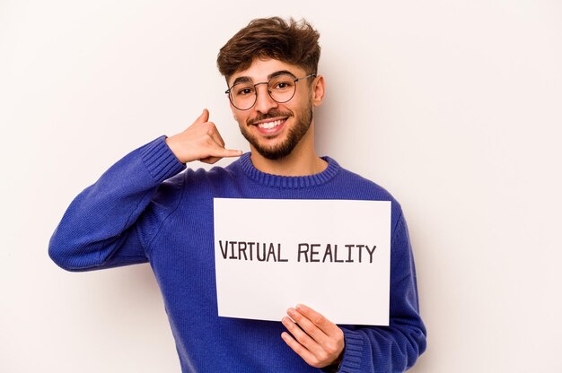 Young hispanic man holding a virtual reality placard isolated on white background showing a mobile phone call gesture with fingers