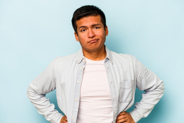 Young hispanic man isolated on blue background sad serious face feeling miserable and displeased