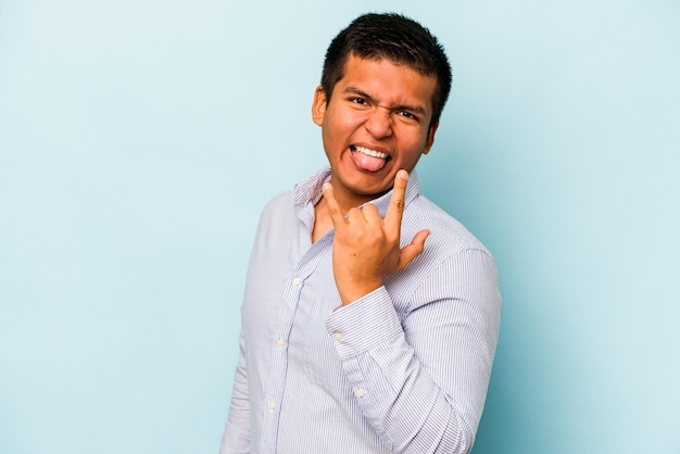 Young hispanic man isolated on blue background showing rock gesture with fingers