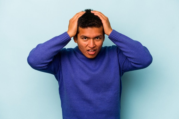 Фото Молодой латиноамериканец, изолированный на синем фоне, удивлен и шокирован