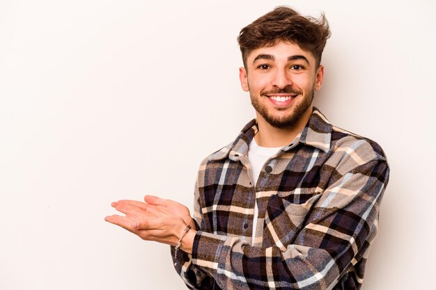 Young hispanic man isolated on white background holding a copy space on a palm