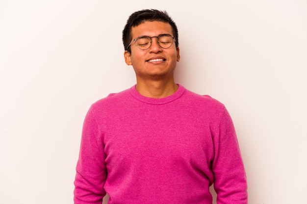 Young hispanic man isolated on white background laughs and closes eyes feels relaxed and happy