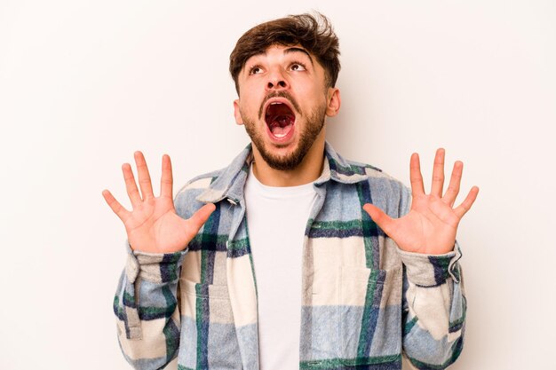 Young hispanic man isolated on white background screaming to the sky looking up frustrated