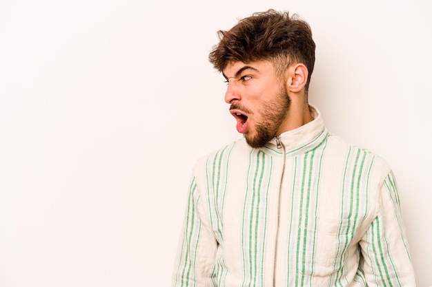 Young hispanic man isolated on white background shouting very angry rage concept frustrated