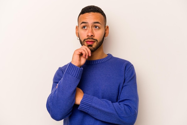 Photo young hispanic man isolated on white background thinking and looking up being reflective contemplating having a fantasy