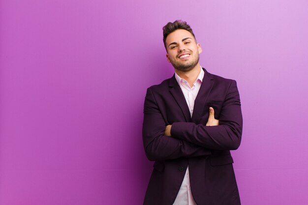 Young hispanic man laughing happily with arms crossed, with a relaxed, positive and satisfied pose