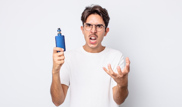 Young hispanic man looking angry, annoyed and frustrated. smoke vaporizer concept