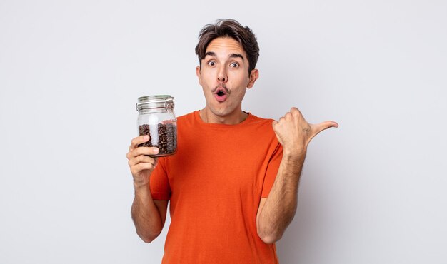 Young hispanic man looking astonished in disbelief. coffee beans concept