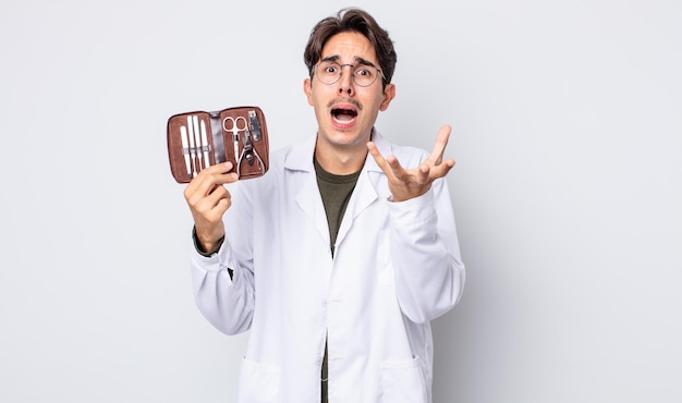 Young hispanic man looking desperate, frustrated and stressed. chiropodist nails tools