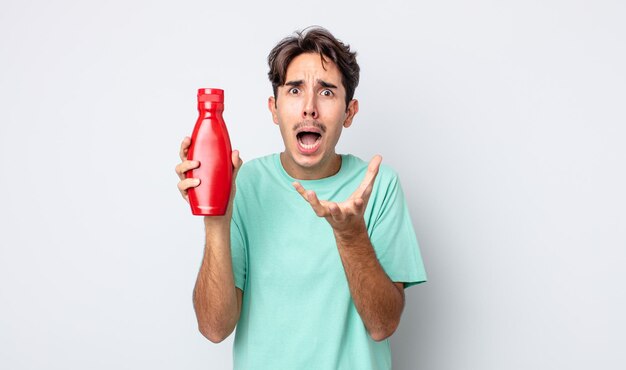 Young hispanic man looking desperate, frustrated and stressed. ketchup concept