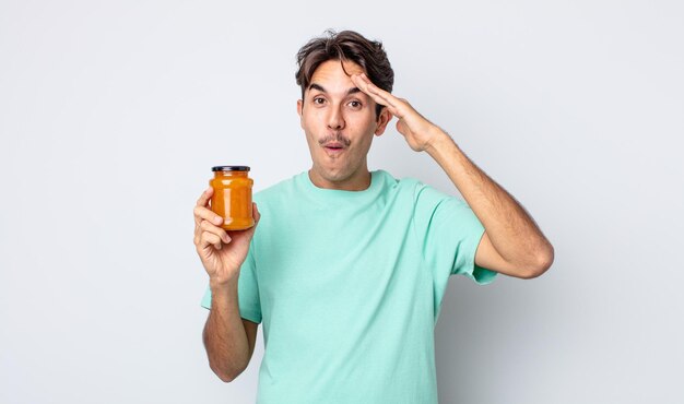 Young hispanic man looking happy, astonished and surprised. peach jelly concept