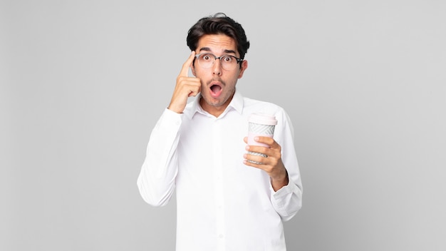 Young hispanic man looking surprised, realizing a new thought, idea or concept and holding a take away coffee