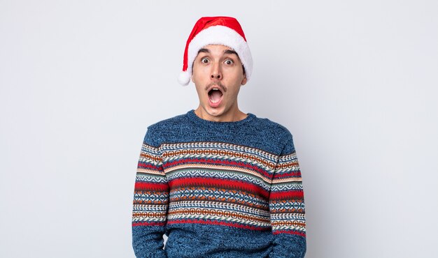 Young hispanic man looking very shocked or surprised. new year and christmas concept