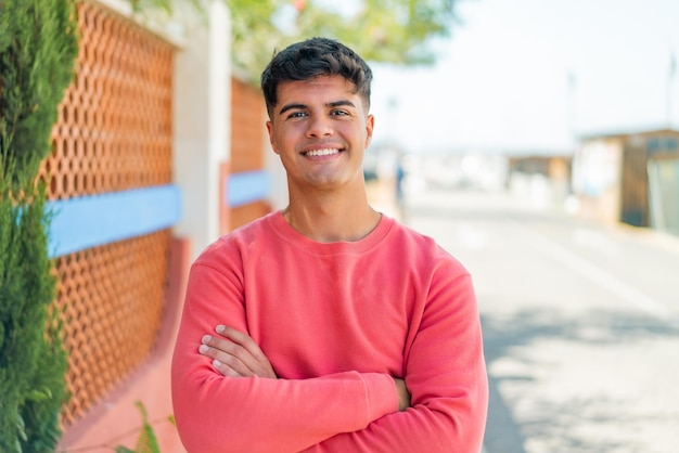 Photo young hispanic man at outdoors keeping the arms crossed in frontal position