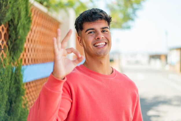 Photo young hispanic man at outdoors showing ok sign with fingers