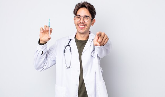 Young hispanic man pointing at camera choosing you. doctor syringe concept