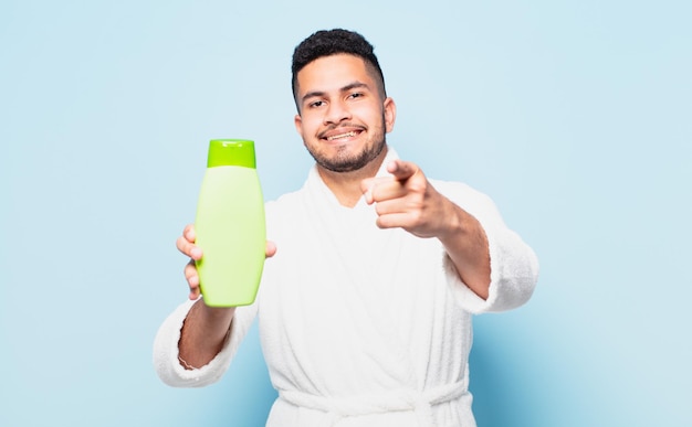 Young hispanic man pointing or showing and wearing a bathrobe