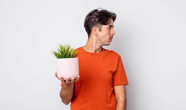 Young hispanic man on profile view thinking, imagining or daydreaming. decorative plant concept