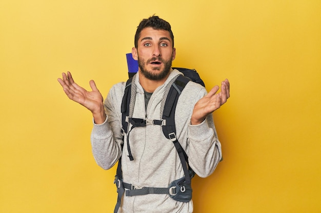 Young Hispanic man ready for hiking surprised and shocked