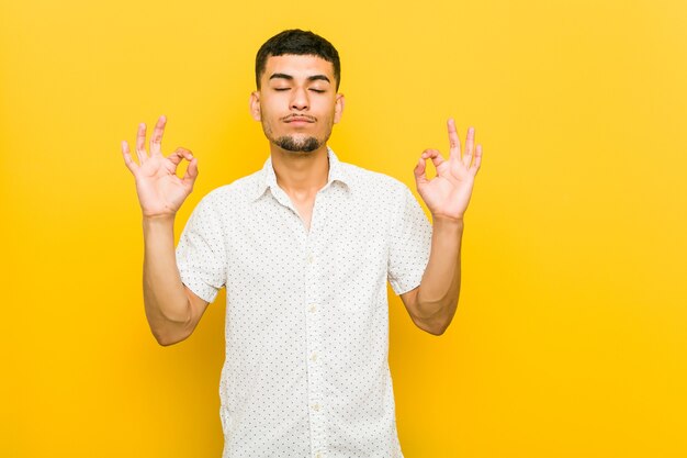 Young hispanic man relaxes after hard working day, she is performing yoga.