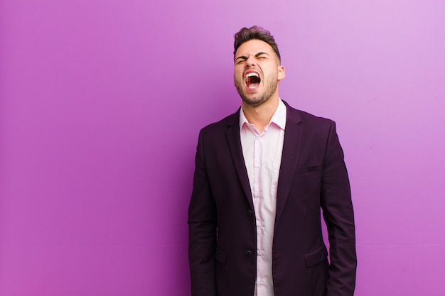 Young hispanic man screaming furiously, shouting aggressively, looking stressed and angry