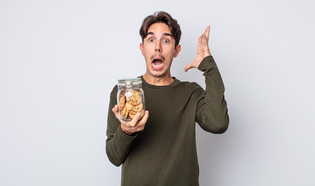 young hispanic man screaming with hands up in the air. cookies concept