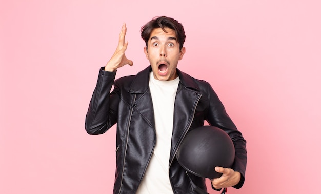 Young hispanic man screaming with hands up in the air. motorbike rider concept