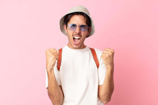 Young hispanic man shouting aggressively with an angry expression. summer concept