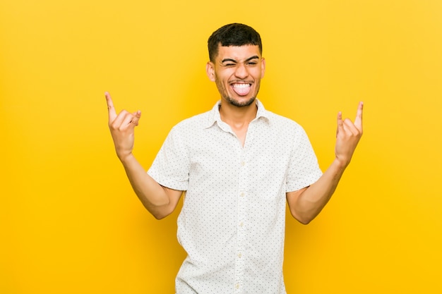 Young hispanic man showing rock gesture with fingers