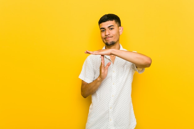 young hispanic man showing a timeout gesture.