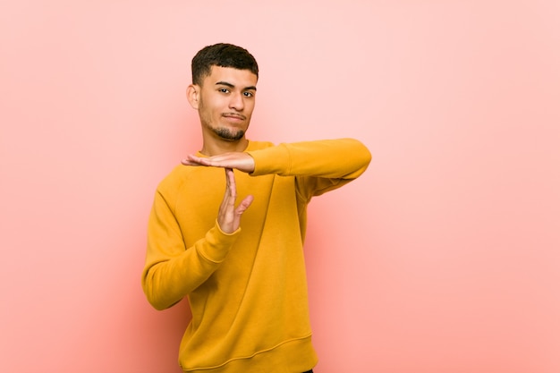 Young hispanic man showing a timeout gesture.