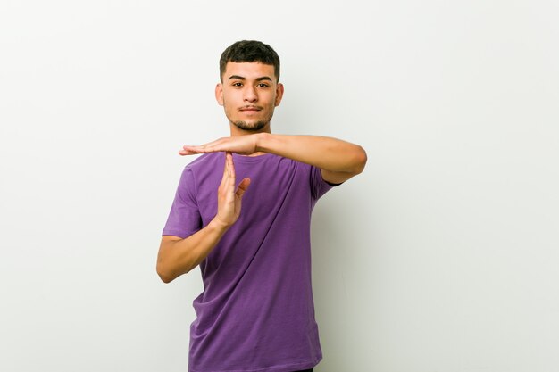 young hispanic man showing a timeout gesture.