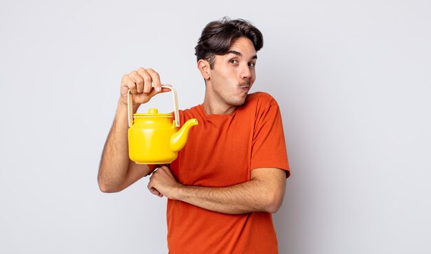 Young hispanic man shrugging, feeling confused and uncertain. teapot concept